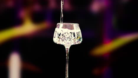 a martini is poured and garnished with olives against a vibrant, blurred background, highlighting the cocktail's elegance