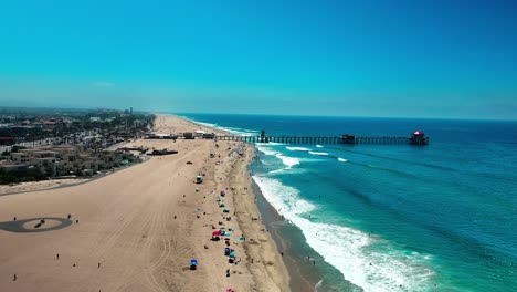 flying over the pacific ocean beach and towards the pier in huntington beach california