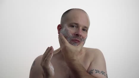 man shaving his face while facing camera in 60fps uhd.