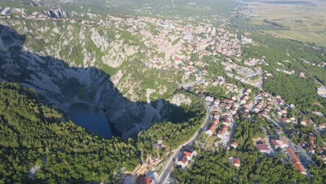 Vista-Aérea-Con-Vistas-Al-Lago-Azul-Y-A-La-Ciudad-De-Imotski-En-La-Soleada-Croacia