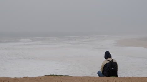 hombre sentado en la orilla del mar