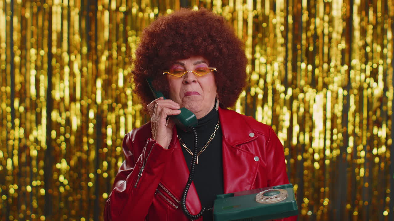 Crazy hotline agent old woman talking on wired vintage telephone of 80s fooling making silly faces