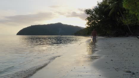 Ein-Mann-Geht-Am-Sandstrand-Der-Insel-Kri-Im-Raja-Ampat-Archipel,-Indonesien-Entlang