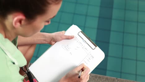 entrenadora escribiendo notas por piscina