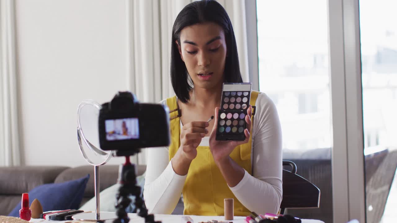 vlogger de género fluido de raza mixta grabando un vlog de maquillaje en casa