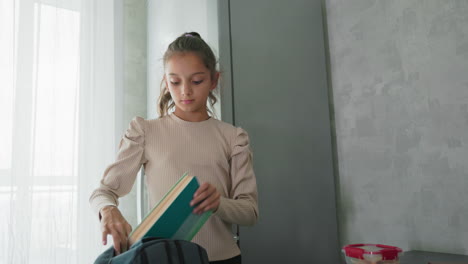 girl and boy in casual clothes packing backpacks in bright kitchen arranging books notebooks water bottles lunchboxes before school commute sibling morning routine domestic daily life
