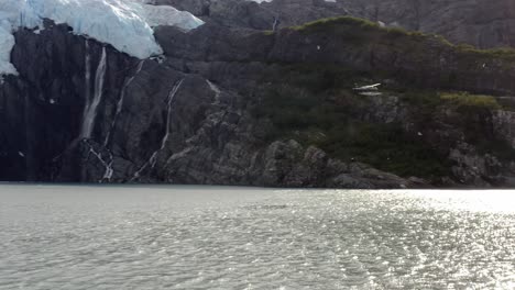 Light-Aircraft-Passing-Through-Snow-Mountain-By-The-Rippling-Ocean-Waters-During-Sunrise-In-Alaska,-USA