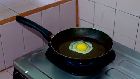 manos rompiendo el huevo en una sartén con aceite hirviendo