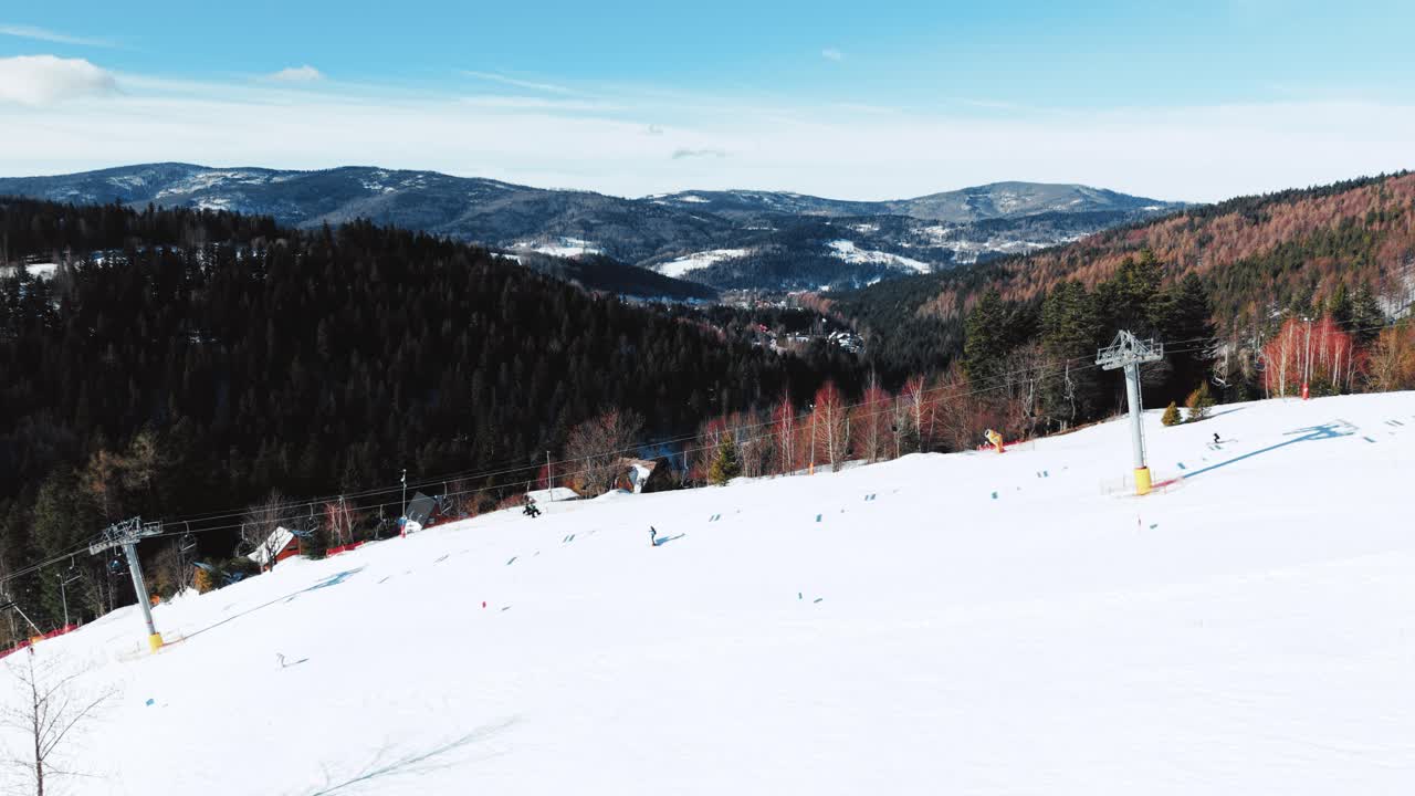 Ripresa da drone di una pista da sci di montagna, skilift e sciatori in una soleggiata giornata invernale.
