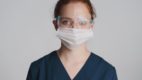 redheaded doctor in front of camera on gray background.