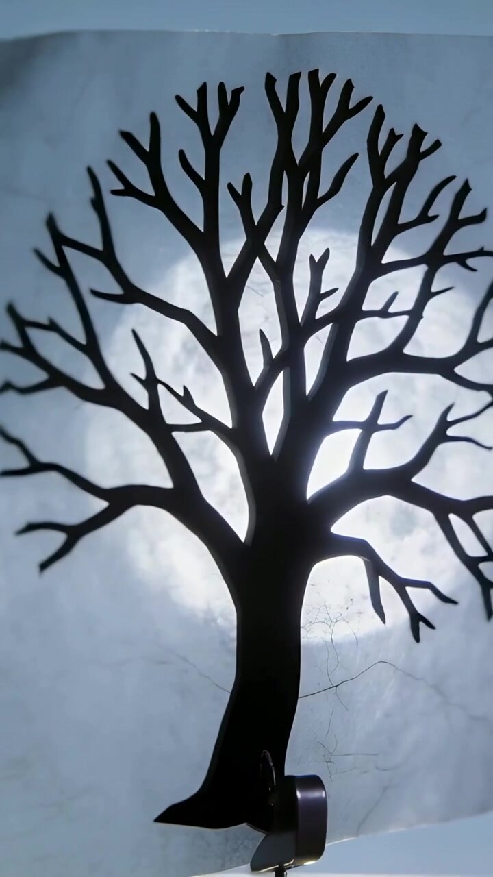 Vertical video: Twisting black tree silhouette on sheet by hand, warping under sun with clip