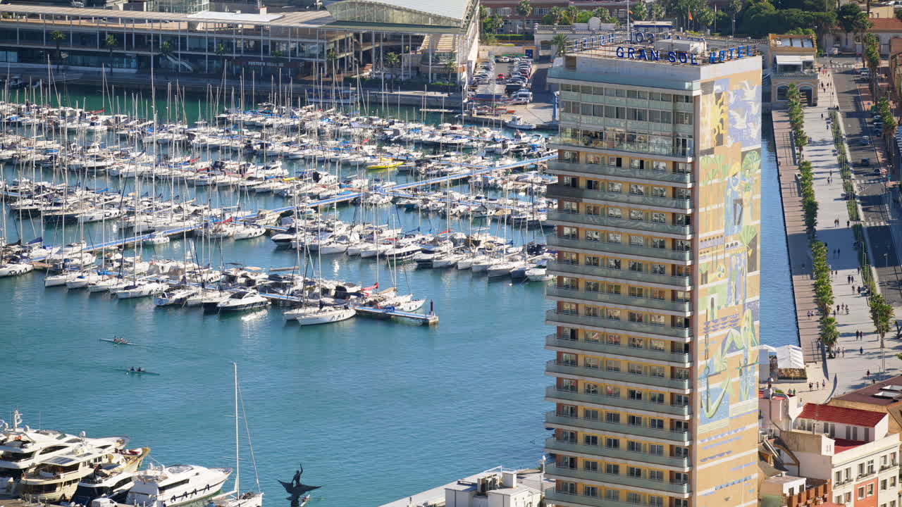 Alicante, Spagna - 26 maggio 2025: Lungomare fiancheggiato da palme accanto al porto, con l'iconica facciata a mosaico dell'Hotel Alicante Gran Sol