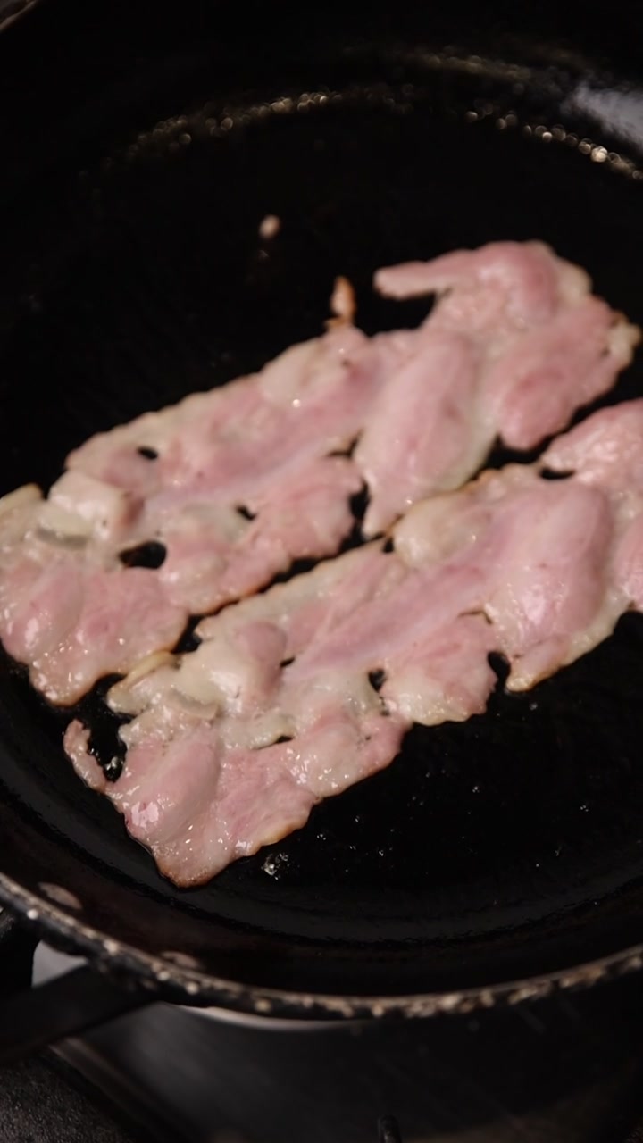 Pancetta cruda che sfrigola in una padella calda