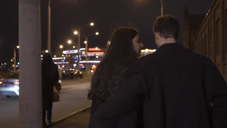 rear view of a couple hugging while they walking in the street after the new year's party