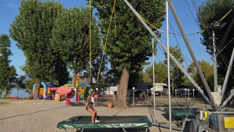 niñas felices tratando de dar la vuelta mientras rebotan en el trampolín con arnés