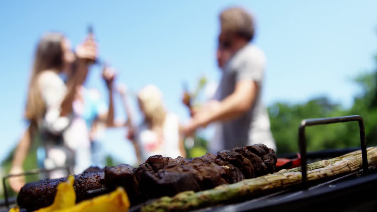 Primo piano di barbecue e amici che festeggiano sullo sfondo