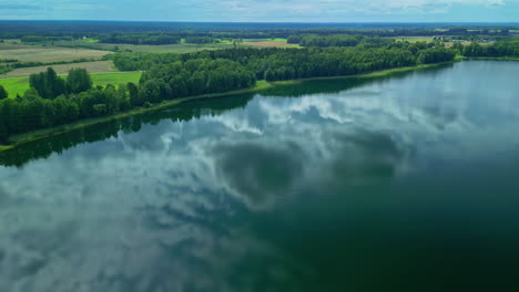 Mirror-like-lake-reflecting-cloudy-sky-with-panoramic-view-of-green-landscape