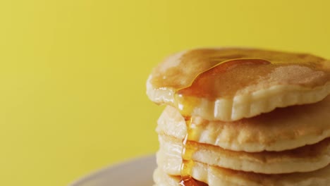 video of maple syrup pouring into pancakes on yellow background