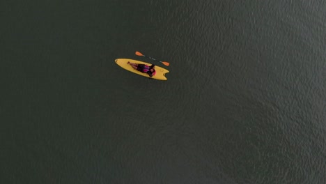 4k aerial top down drone shot of a 28-year-old indian male relaxing on a kayak in the backwaters of varkala, kerala