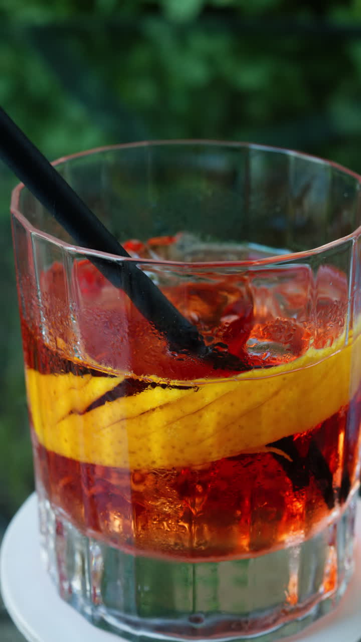 Primo piano di un cocktail Negroni su sfondo verde. Verticale