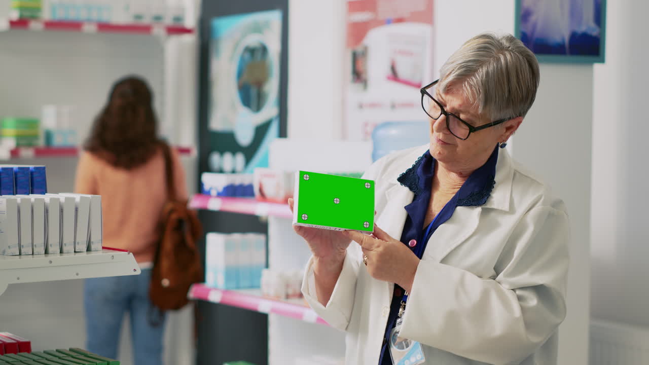 Pharmacist presenting medicine box with green screen in pharmacy