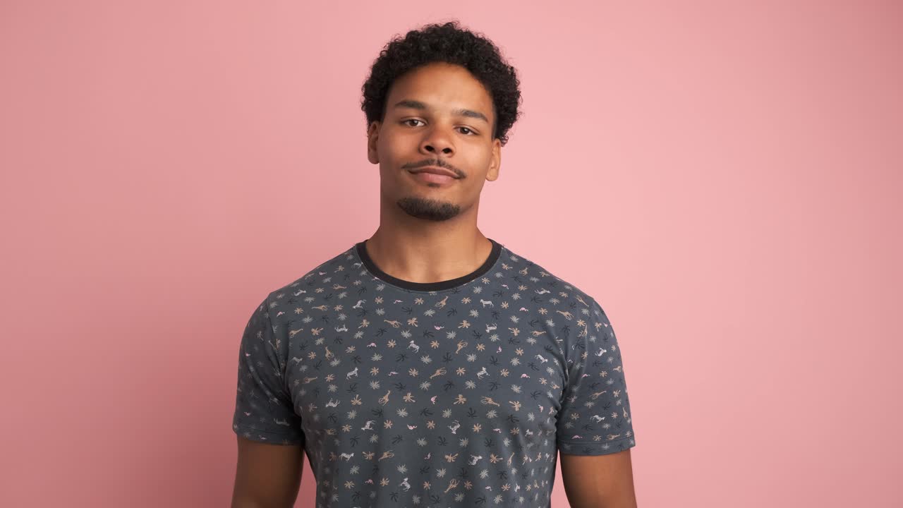 Smiling young man looking at camera in pink studio