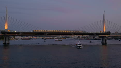 el barco de ferry de la noche navega bajo el iluminado puente de metro del cuerno dorado de estambul