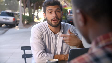 shot of two male friends with coffees outside coffee shop