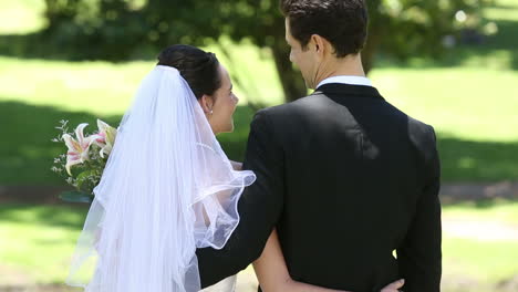 happy newlyweds standing in the park