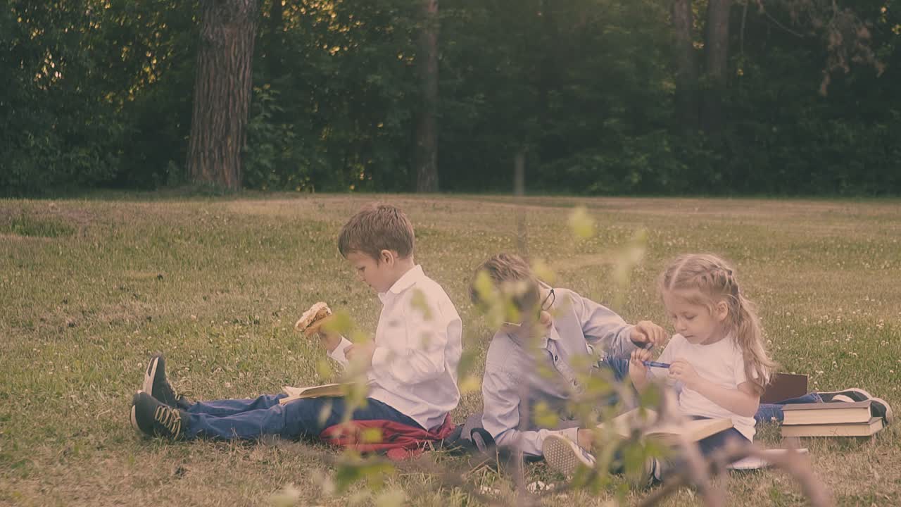 작은 소년은 여자 친구  ⁇ 에 앉아 연필을 날카롭게 도와줍니다.