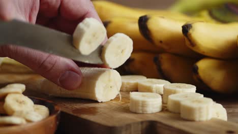 male hands slicing the banana into pieces.