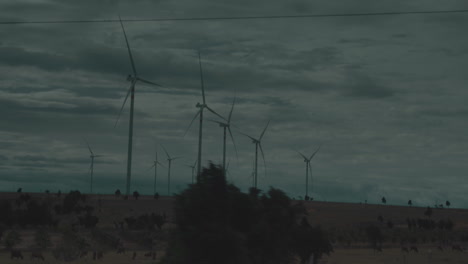 las turbinas eólicas extendidas por el campo abierto en las llanuras de pastizales en un día de tormenta