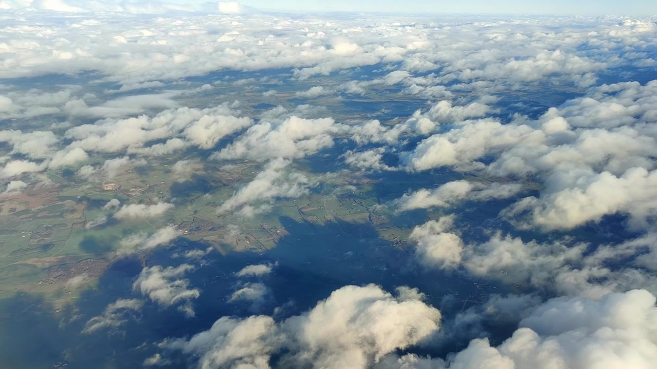 Campagna danese con luce solare e ombre da nuvole sparse sottostanti. Vista da un aereo ad alta quota.