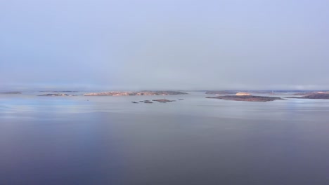 flying over the peaceful, calm waters of lysekil, sweden with the horizon and small islands in the distance - aerial shot