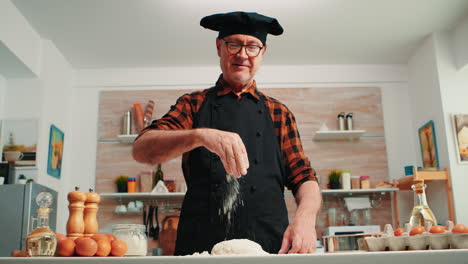 adding flour on dough by hand looking at camera