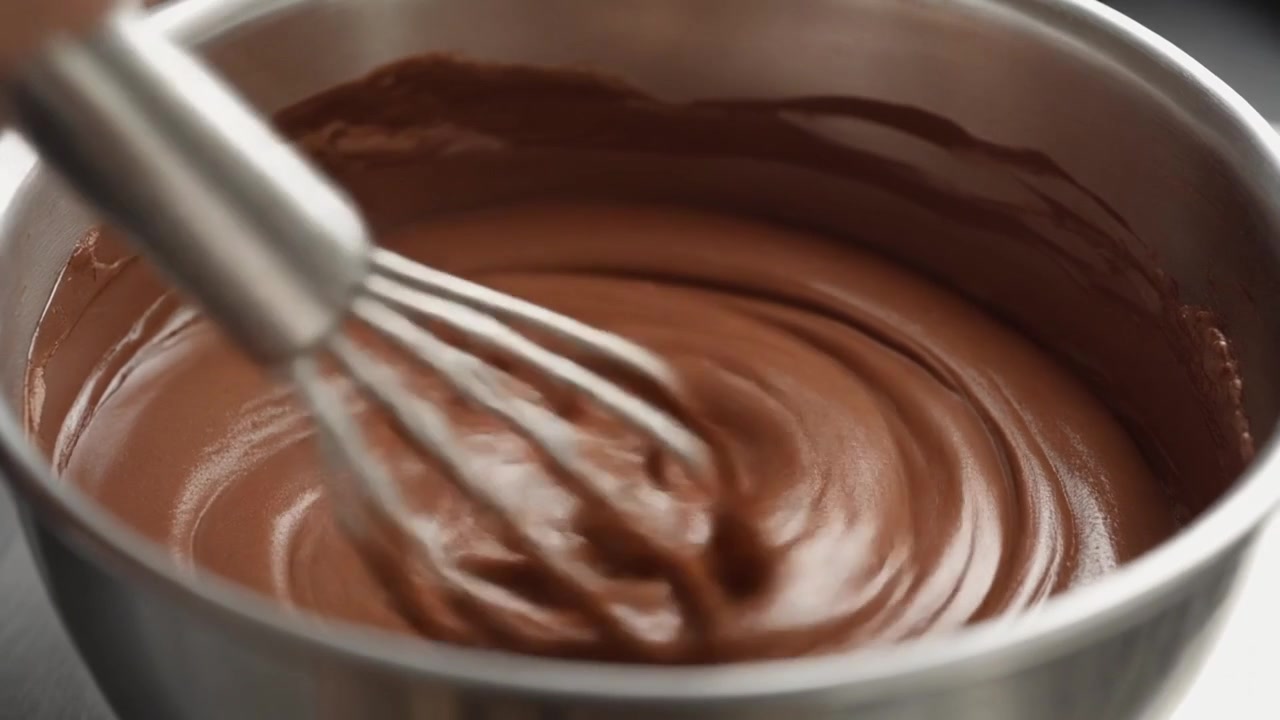 Mescolare cioccolato fuso liscio in una ciotola di metallo