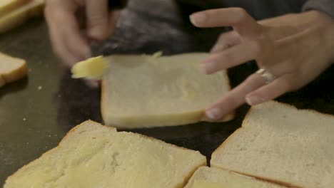 mujer joven ocupada untando pan con mantequilla para hacer sándwiches a la barbacoa para el almuerzo