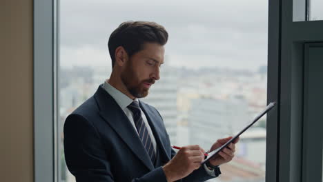 hombre de negocios leyendo los términos del contrato sintiéndose satisfecho en la ventana de la oficina de cerca.