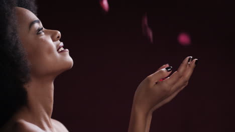 retrato atractiva joven mujer afroamericana soplando pétalos de rosa cayendo en las manos hermosa mujer con concepto de día de san valentín afro