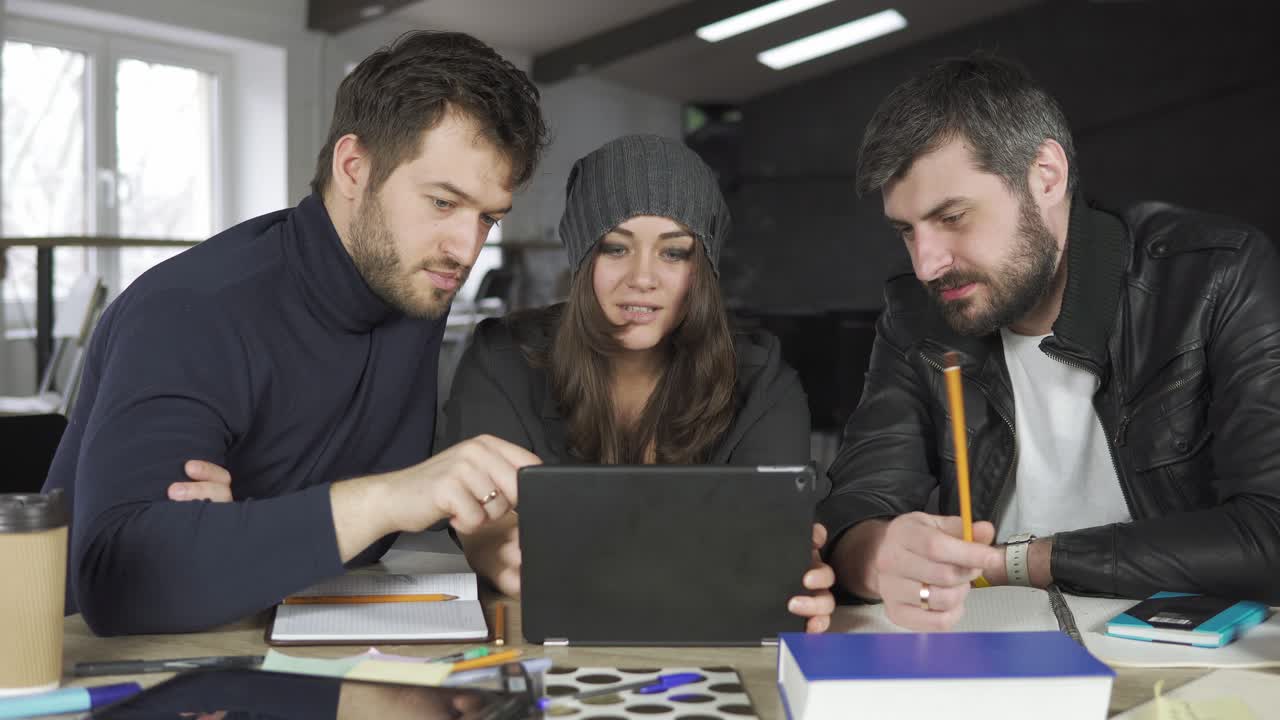 equipo de jóvenes profesionales teniendo una reunión en una oficina creativa. mirando la pantalla de una tableta. discusión de negocios. tazas de café en la mesa. filmado en 4k