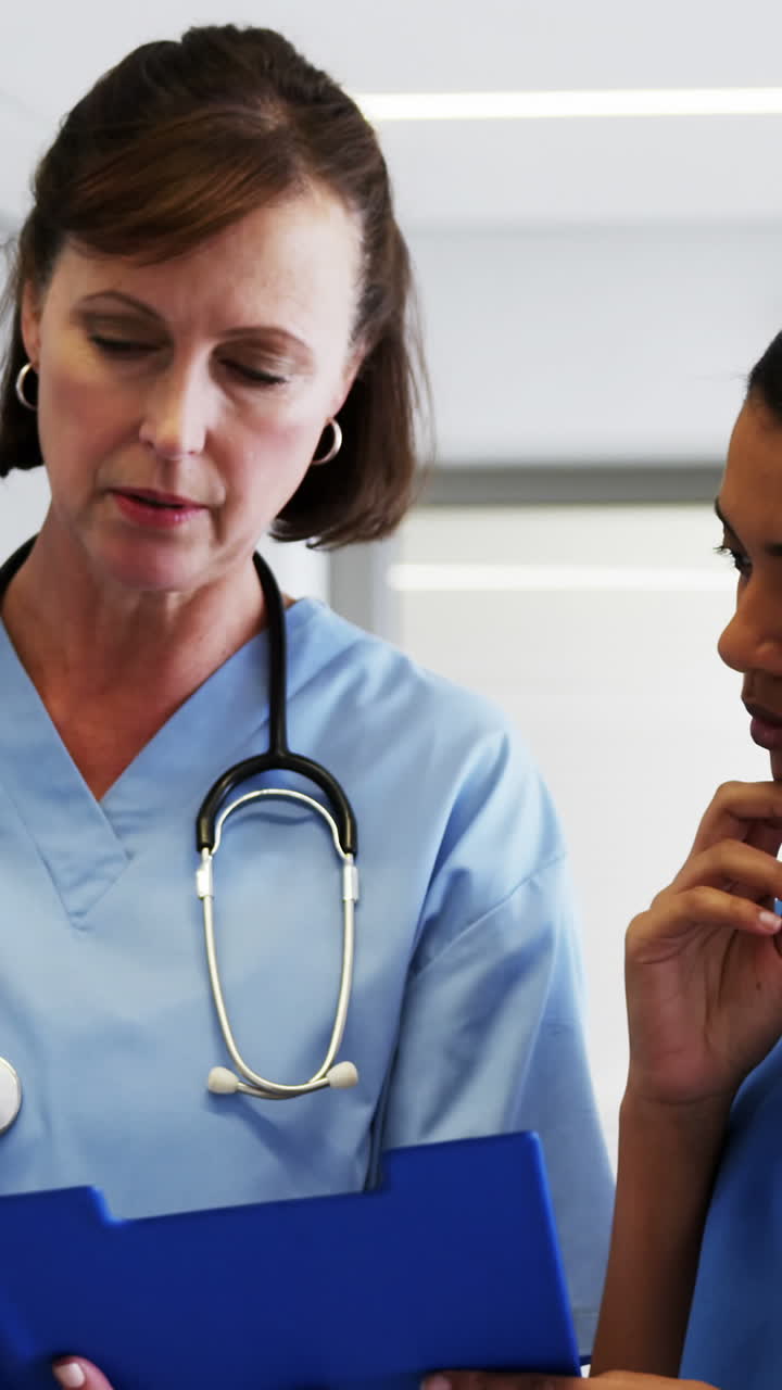 Nurse and doctor discussing over clipboard