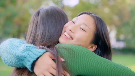two young women happily hugging outdoors