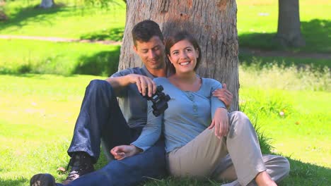 una pareja de jóvenes enamorados apoyados en un árbol
