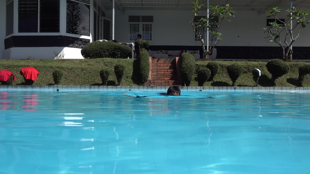 niño con gafas de natación disfrutando nadando en la piscina al estilo rana