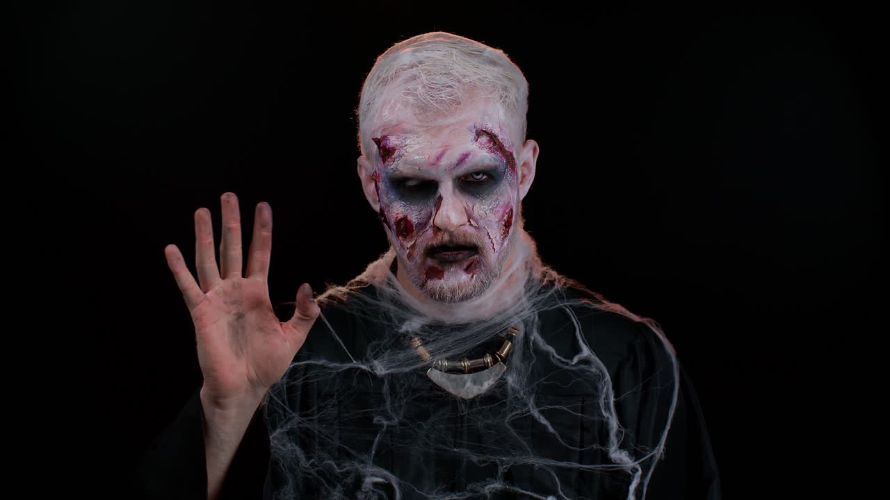 espeluznante halloween hombre zombi sonriendo amistosamente agitando las manos gestando hola o adiós, bienvenida