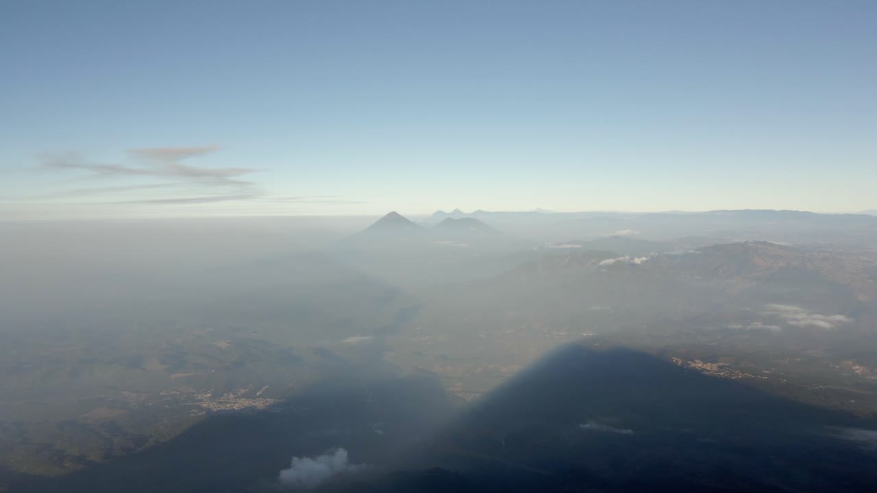 Panoramic aerial establishing pullback of landscape below Volcano Acatenango, mist covered slopes with view of the valley