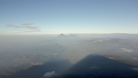 Panoramic aerial establishing pullback of landscape below Volcano Acatenango, mist covered slopes with view of the valley