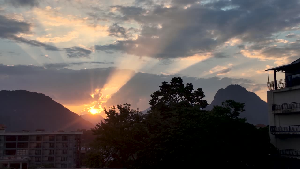 Raios de sol da tarde iluminando montanhas cársticas e nuvens durante o pôr do sol em Vang Vieng