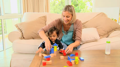 young mother playing with her baby with building blocks