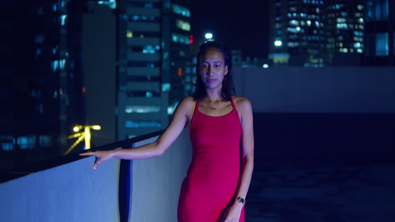 Le luci vivaci di Port of Spain, Trinidad nei Caraibi fanno da sfondo a una ragazza ispanica su un tetto
